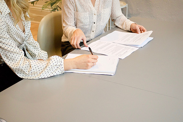 Anträge auf dem Schreibtisch mit Händen von zwei Personen darauf